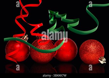 Il rendering 3D mostra quattro palline rosse sulla superficie nera con un albero a nastro verde e ricci rossi Foto Stock
