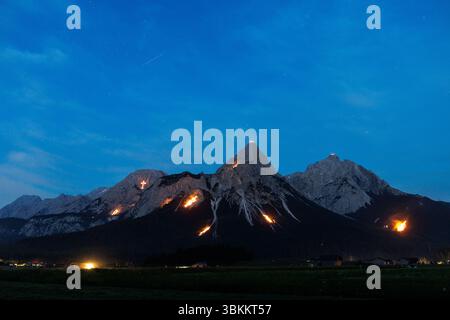 Lermoos, Austria. Lermoos, Austria. 21 giugno 2025. Numerosi fuochi si possono vedere sulle montagne nella Tirolese Zugspitz Arena nel bacino della valle Ehrwald Lermoos e Biberwier in Tirolo (Austria) il 21.06.2025 per il solstizio d'estate. L'immagine mostra l'Ehrwalder Sonnenspitze nel Mieminger Kette. Ogni anno, il giorno più lungo e la notte più breve vengono celebrati nella regione con spettacolari fuochi d'artificio. All'imbrunire, il cosiddetto "Bergfeurer" accende gli incendi di mezza estate, che poi bruciano nella notte. Credito: dpa Picture Alliance/Alamy Live News Foto Stock