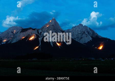 Lermoos, Austria. Lermoos, Austria. 21 giugno 2025. Numerosi fuochi si possono vedere sulle montagne nella Tirolese Zugspitz Arena nel bacino della valle Ehrwald Lermoos e Biberwier in Tirolo (Austria) il 21.06.2025 per il solstizio d'estate. L'immagine mostra l'Ehrwalder Sonnenspitze nel Mieminger Kette. Ogni anno, il giorno più lungo e la notte più breve vengono celebrati nella regione con spettacolari fuochi d'artificio. All'imbrunire, il cosiddetto "Bergfeurer" accende gli incendi di mezza estate, che poi bruciano nella notte. Credito: dpa Picture Alliance/Alamy Live News Foto Stock