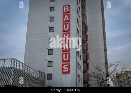Un alto edificio Bauhaus grigio con un cartello rosso verticale che mostra il nome dell'azienda. Architettura moderna e concetto di vendita al dettaglio. Berlino, Germania. 29 marzo Foto Stock