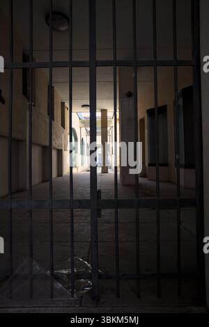 Passaggio parzialmente all'ombra tra edifici bloccati da un cancello di ferro Foto Stock