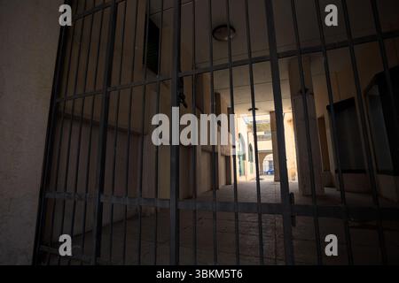 Passaggio parzialmente all'ombra tra edifici bloccati da un cancello di ferro Foto Stock