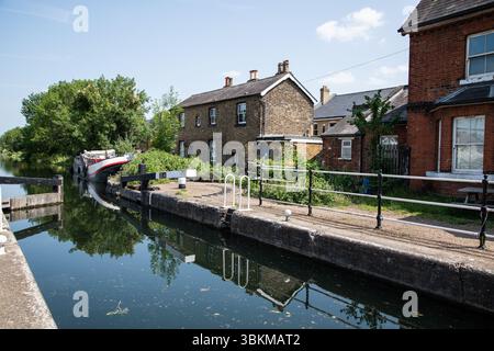 Enfield Lock in una giornata di sole, che mostra le storiche porte del canale, le acque calme e la vegetazione circostante in un clima luminoso e limpido. Foto Stock
