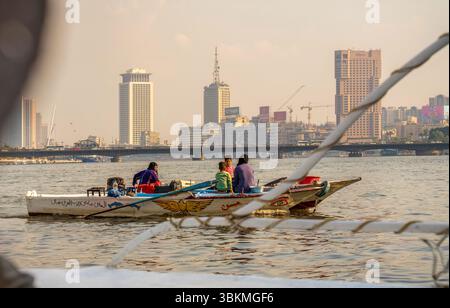 Cairo, Egitto - 11 settembre 2023: Una vivace scena fluviale che mostra un gruppo che si gode un tradizionale giro in barca con lo skyline del Cairo come sfondo. Il Foto Stock