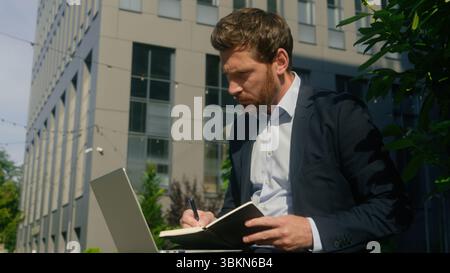 Note di scrittura concentrate idea pensive soluzione di riflessione lavoro Internet digitazione computer Caucasico uomo d'affari di mezza età uomo d'affari adulto Foto Stock
