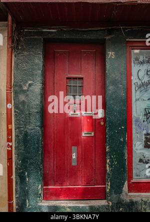 Una porta d'ingresso rossa adornata con mobili per porte lungo una stretta strada nella parte vecchia di Porto, Portogallo. Foto Stock