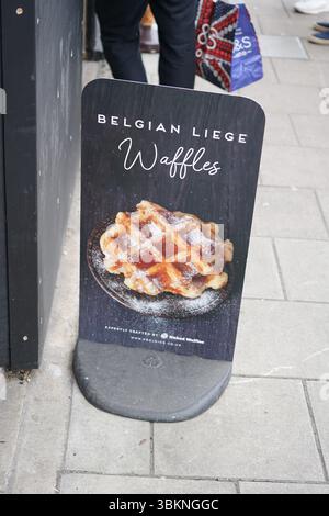 Insegna promozionale con deliziosi waffle belgi di Liegi su un marciapiede della città. Guildford, Inghilterra Foto Stock