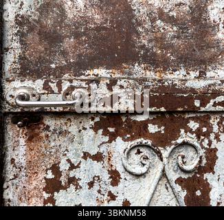 Dettaglio della porta in metallo arrugginito vintage con maniglia in ferro e scrollwork, che mostra vernice sbucciata e texture grunge. Utile per CGI e sfondi di gioco Foto Stock