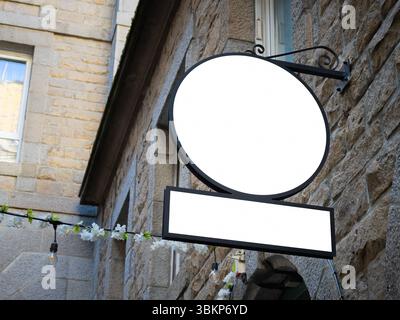 Mockup di cartelli editabili su un muro di pietra con pannelli rotondi e rettangolari. Vista stradale angolata ideale per la presentazione di marchi o logo in urban conte Foto Stock