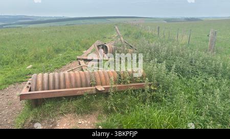 Rusty abbandonò i rulli agricoli che riposavano nell'erba sovrastata, mostrando metallo intempestivo e decadimento rurale nella campagna scozzese. Foto Stock