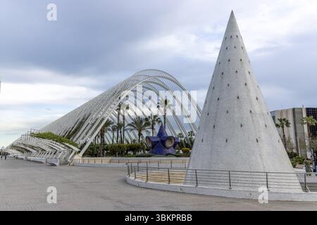 Edificio conico fiancheggiato da piastrelle di ceramica bianca e un edificio culturale multifunzionale El Umbracle con tetto semicircolare, palme sa Foto Stock
