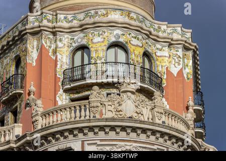 Dettaglio della parte superiore decorata dell'edificio del Banco de Valencia (edificio del Banco de Valencia), del 1942, con facciata color arancio e ceramica Foto Stock