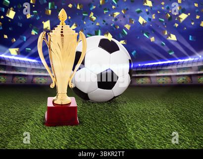 Campionato di calcio. Coppa dei trofei dorata e palla da calcio sotto i coriandoli cadenti sullo stadio Foto Stock