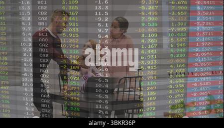 Famiglia di tre persone che si riuniscono al tavolo di legno in cucina, con quaderni a spirale, tazze e sovrapposizione dati Foto Stock