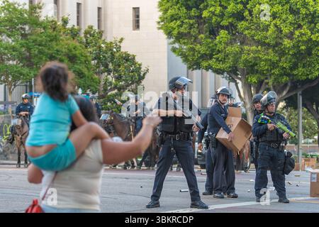 Los Angeles, USA, 8 giugno 2025 la madre con un bambino sulle spalle grida slogan all'agente di polizia durante una manifestazione in centro contro Expanded i Foto Stock