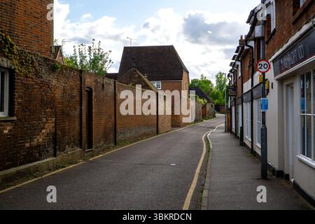 Una pittoresca scena di strada a Saffron Walden, Essex, Regno Unito, caratterizzata da un muro di mattoni, edifici e una strada stretta Foto Stock