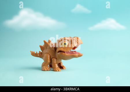 Il simpatico mini stegosauro dan in plastica in azione su sfondo azzurro nuvoloso Foto Stock