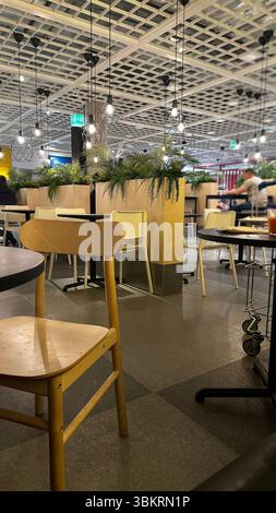 Interno di un elegante ristorante con soffitto in legno sospeso, divisori e piante, comodi tavoli rotondi con sedie in legno. Foto Stock