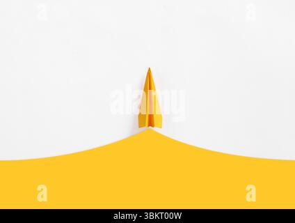 Composizione minimalista con un aeroplano di carta gialla che si innalza sopra una linea gialla curva, simboleggiando viaggi o startup aziendali Foto Stock