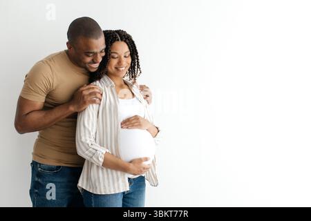 Ritratto di donna nera incinta e suo marito che abbraccia a casa Foto Stock