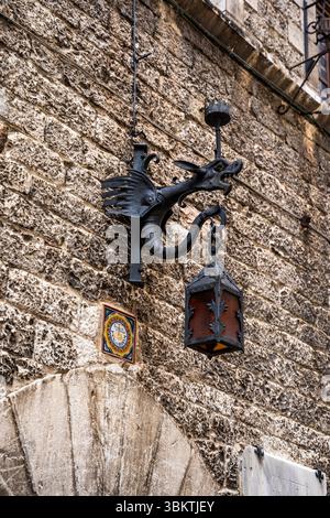 Lanterna decorativa in ferro battuto a forma di drago su un muro di pietra nel centro storico medievale di Assisi, Umbria, Italia Foto Stock