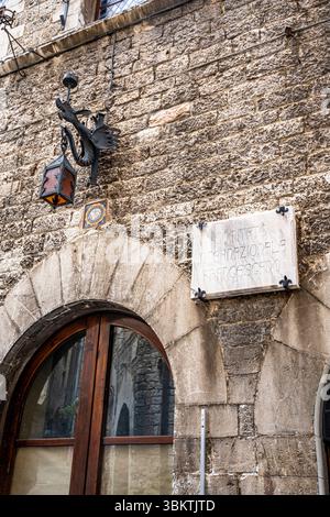 Lanterna decorativa in ferro battuto a forma di drago su un muro di pietra nel centro storico medievale di Assisi, Umbria, Italia Foto Stock