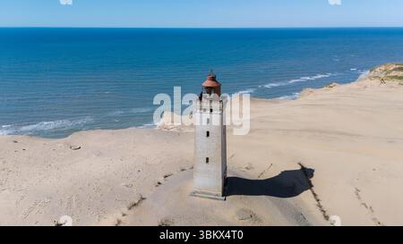 Un'impressionante vista del faro di Rubjerg Knude, arroccato su una scogliera sabbiosa, che si affaccia sul Mare del Nord in Danimarca. Questo monumento storico attira i visitatori per la sua ricca storia e le vedute mozzafiato. Foto Stock