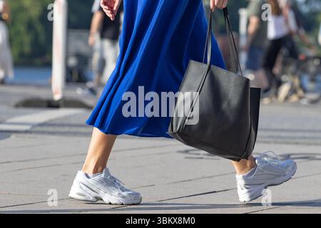 donna con abito blu e borsa in pelle nera Foto Stock