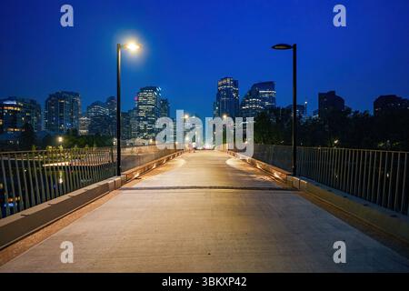 Ponte di Jaipur che attraversa il fiume Bow da Prince's Island verso il centro di Calgary al crepuscolo in Alberta, Canada Foto Stock