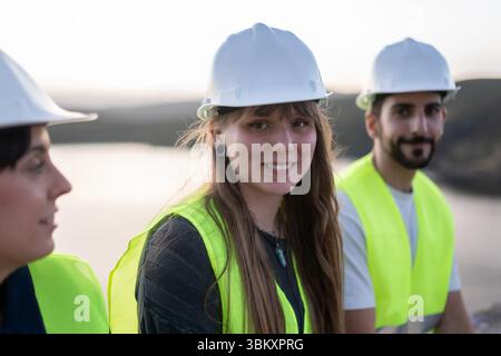 Giovani ingegneri che indossano giubbotti di sicurezza e caschi per promuovere la carriera tecnica Foto Stock