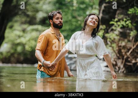 La coppia gode di un momento sereno insieme vicino a un fiume che scorre nella natura Foto Stock