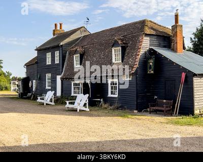Vecchie case tradizionali in legno, con bordo resistente alle intemperie e dipinte di nero, sull'isola privata di Osea, sull'estuario Blackwater, Essex, Regno Unito Foto Stock