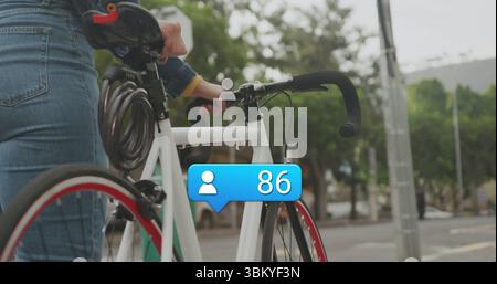 Tenendo in mano la bici bianca, donna che indossa una giacca in denim sul marciapiede della città, con 86 follower Foto Stock