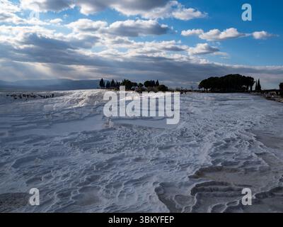 Pamukkale, Turchia, è un sito naturale che contiene sorgenti termali e travertini, terrazze di minerali carbonatici lasciati dall'acqua corrente. La gente visita per vedere il paesaggio unico e fare il bagno nelle acque ricche di minerali. Foto Stock