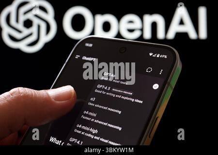 Utente che interagisce con il selettore del modello ChatGPT sul telefono con il logo OpenAI dietro. Stafford, Regno Unito, 23 giugno 2025 Foto Stock