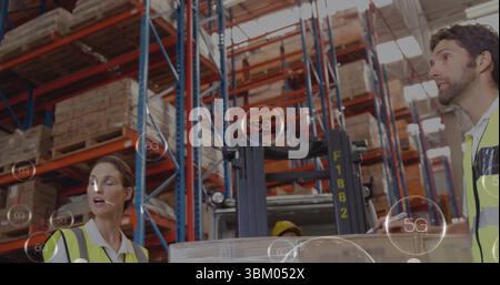 Personale di magazzino che coordina il funzionamento dei carrelli elevatori nello stabilimento, con scaffali e attrezzatura di sicurezza Foto Stock
