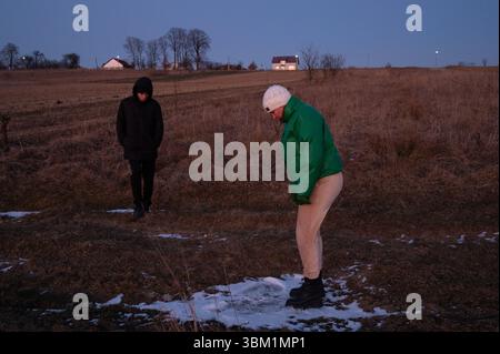 Due persone si godranno una passeggiata serale in una tranquilla campagna, una osservando mentre l'altra interagisce con una zona di gelo a terra come al crepuscolo Foto Stock