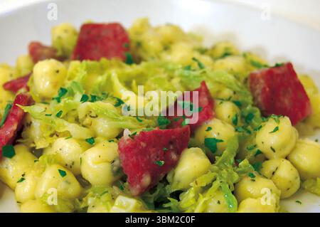 Vista ravvicinata di un delizioso piatto a base di gnocchi di patate, perfettamente conditi con cavolo sabaudo e salato carne di maiale salata, il tutto meravigliosamente garnishe Foto Stock
