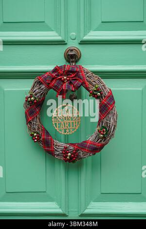 La corona decorativa di Natale è appesa su una porta d'ingresso di una casa a Kensington, Londra, Inghilterra, Regno Unito, Regno Unito Foto Stock