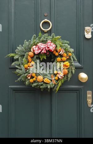La corona decorativa di Natale è appesa su una porta d'ingresso di una casa a Kensington, Londra, Inghilterra, Regno Unito, Regno Unito Foto Stock