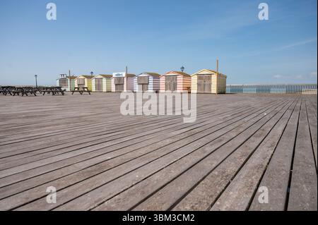 Rifugi sulla spiaggia a strisce di colori diversi a Hastings nelle giornate di sole Foto Stock