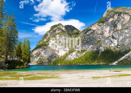 Angolo appartato del Lago Braies con le sue acque turchesi che incontrano una riva dai colori chiari, incorniciata da montagne torreggianti e aspre e da un verde lussureggiante Foto Stock