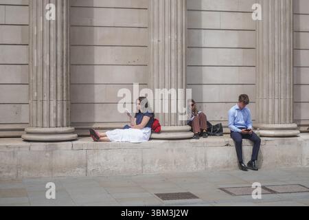 Londra, Regno Unito. 24 giugno 2025. Lavoratori della città che si rilassano sotto il sole fuori dalla Bank of England nella città di Londra in una giornata calda e umida, mentre un'altra ondata di caldo è prevista questo fine settimana con temperature che dovrebbero raggiungere i 30 gradi Celsius Amer Ghazzal/Alamy Live News Foto Stock