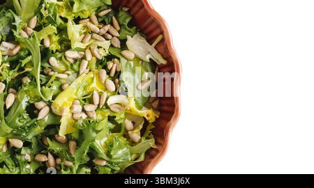 Insalata verde fresca e sana con semi di girasole. Spazio di copia vuoto sul lato destro. Cibo vegetariano naturale. Vista dall'alto in un recipiente in ceramica. Foto Stock