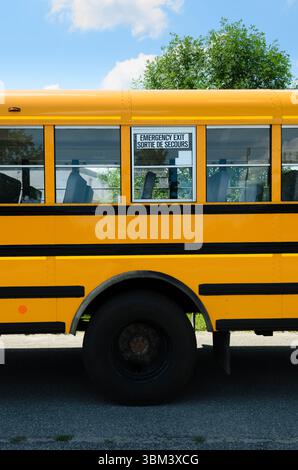 Finestra di uscita di emergenza sul lato di uno scuolabus sopra la ruota posteriore. Foto Stock