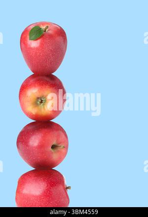 Mele rosse impilate una sopra l'altra su sfondo azzurro. Equilibrio Foto Stock