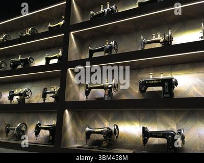 Macchine da cucire d'epoca esposte su scaffali in legno, evocando nostalgia e artigianalità, mostrando il design industriale e la storia domestica in un fascino Foto Stock
