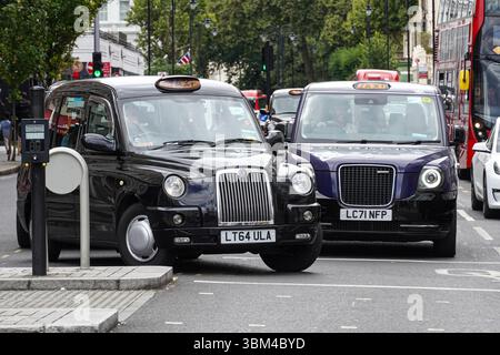 Taxi nero elettrico vecchio e nuovo a Londra Inghilterra Regno Unito Regno Unito Foto Stock