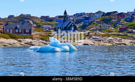 Paesaggio urbano artico panoramico con case colorate sulla costa rocciosa e ghiaccio azzurro in primo piano nella città polare di Ilulissat, in Groenlandia Foto Stock