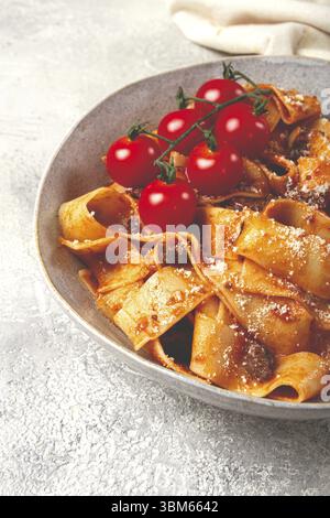 Pappardelle con salsa alla bolognese, condita con parmigiano e rametto di ciliegia, fatta in casa, non c'è gente Foto Stock